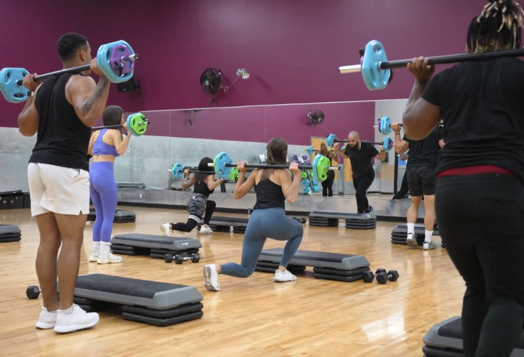 10GYM Broken Arrow members performing weighted lunges during a boot camp group fitness class