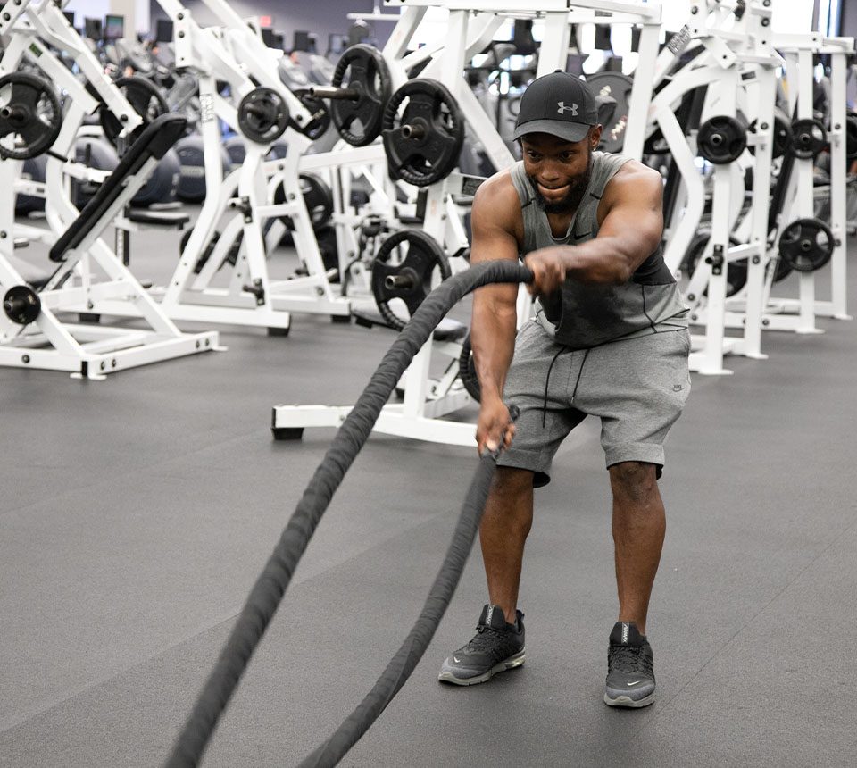 Gym member working out with battle ropes