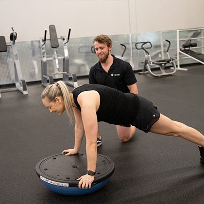 personal trainer working with client on a bosu ball