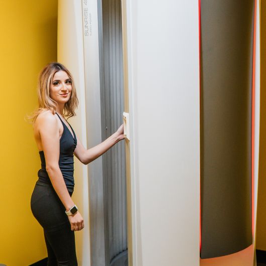 Member using the standing tanning bed at 10GYM Jenks.