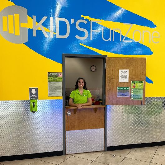 a 10gym south tulsa team member works the desk at the kidz fun zone onsite childcare area