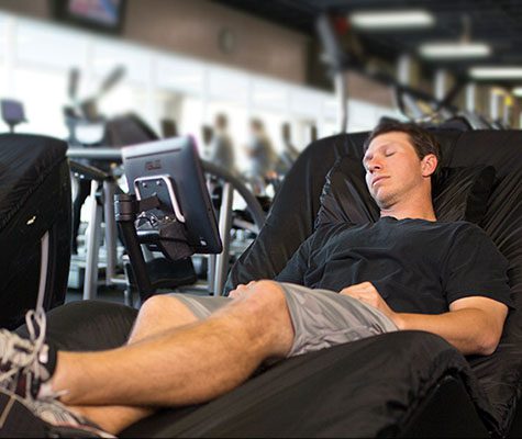 man relaxing and recovering in a hyromassage chair in modern gym