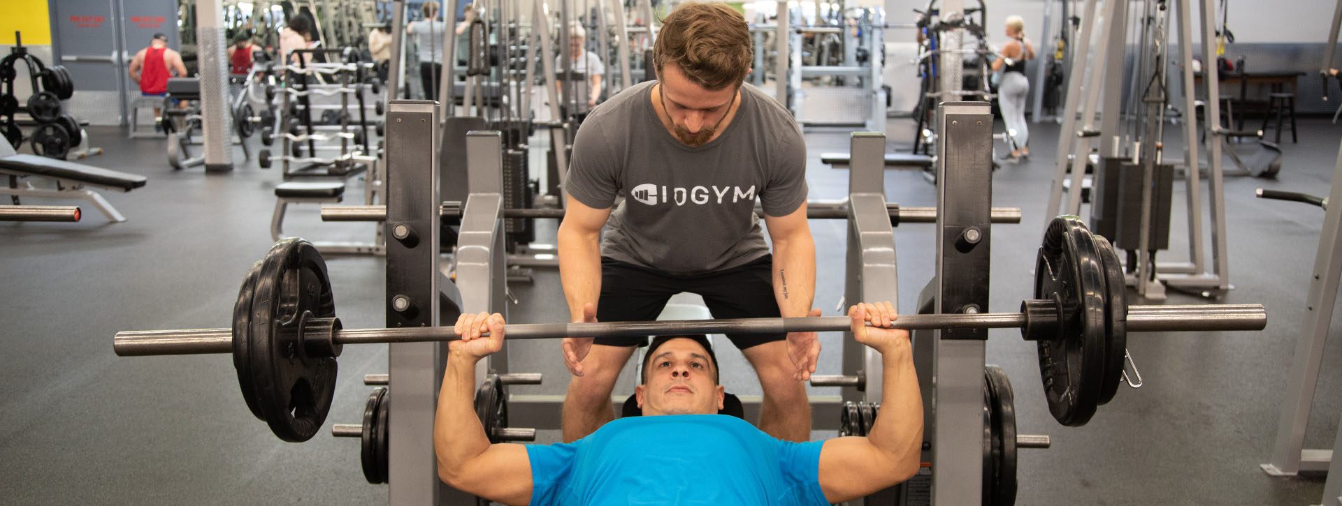 personal trainer working with gym member in modern gym near me