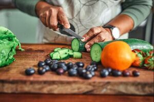 Person slicing vegetables for nutritious meal inspired by the best gym near you.