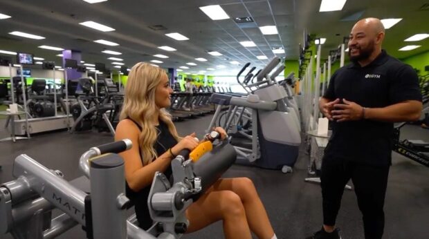 Gym member discusses fitness with personal trainer.