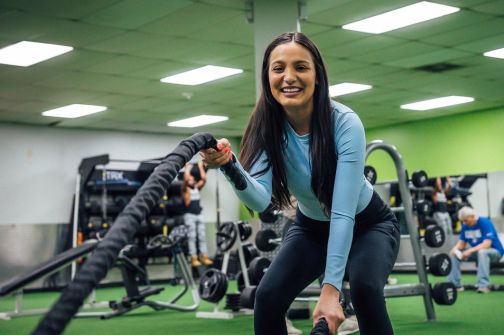 Girl wearing blue top exercising with battle ropes in the functional training area at 10GYM.