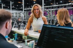 Friendly 10GYM team member welcoming guests at the front desk of one of our OK & AR gyms.