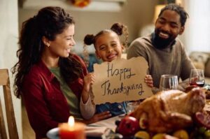 Family enjoying Thanksgiving dinner together with a roasted turkey and festive holiday meal.
