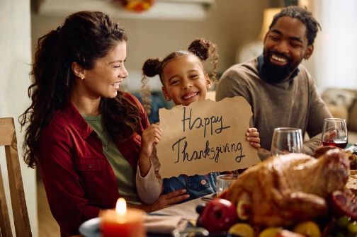 Family enjoying Thanksgiving dinner together with a roasted turkey and festive holiday meal.